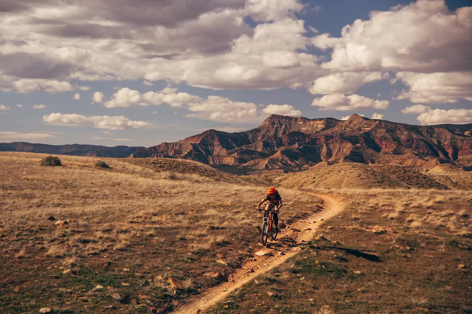 Person on mountain bike biking on trail in Colorado with mountains in background